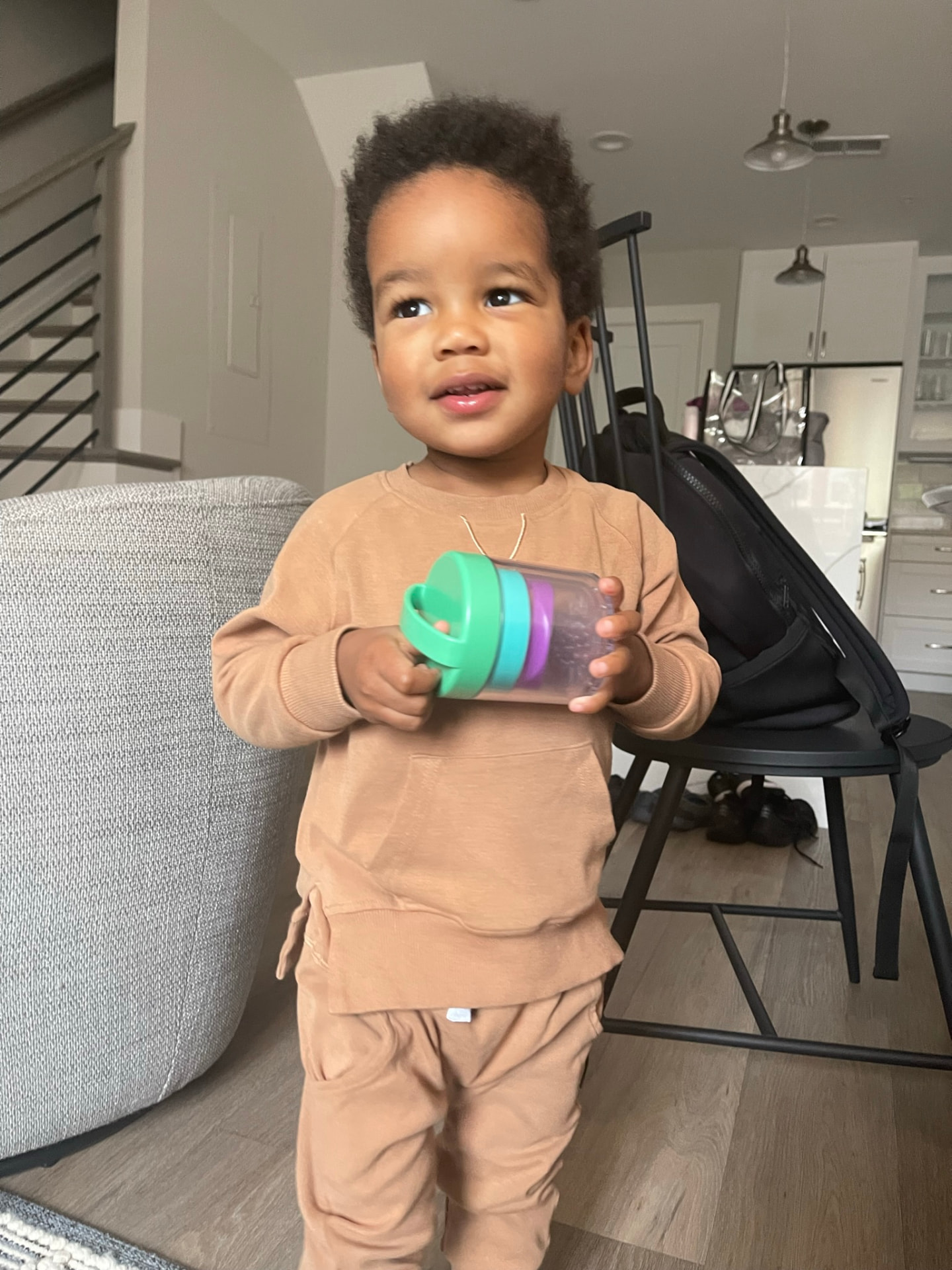 Toddler standing in the living room of the Old Town Alexandria apartment holding a snack cup
