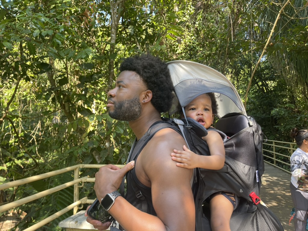 A parent carrying a toddler in an Osprey Poco Lite carrier on a jungle trail in Costa Rica