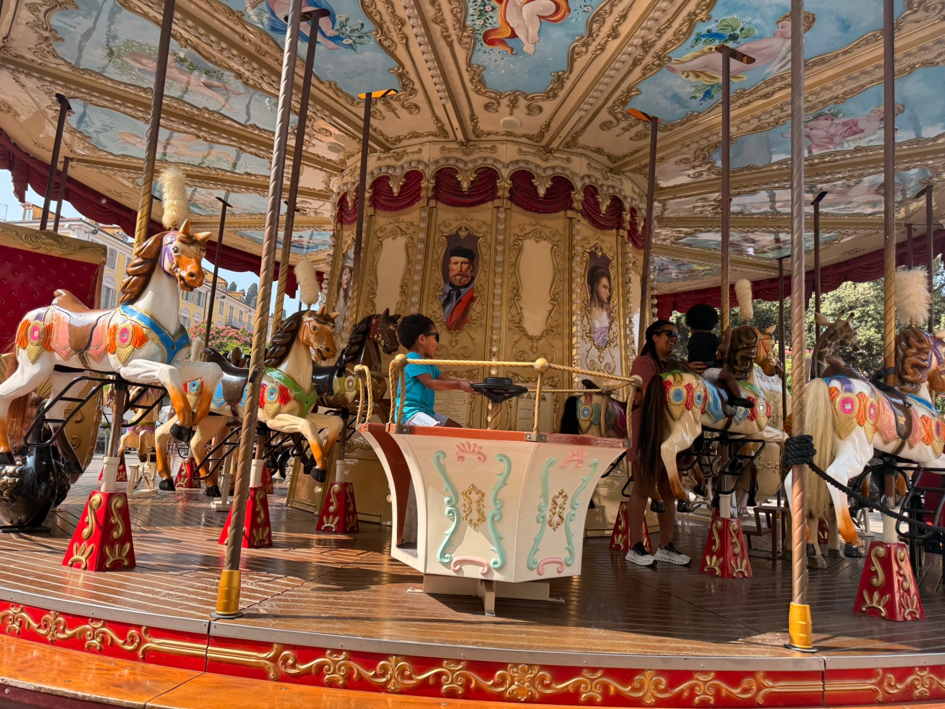A child riding a colorful vintage carousel at Place Garibaldi in Nice.