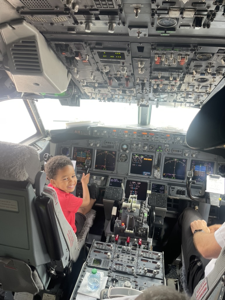 Young boy smiling in the captain's seat of an airplane cockpit