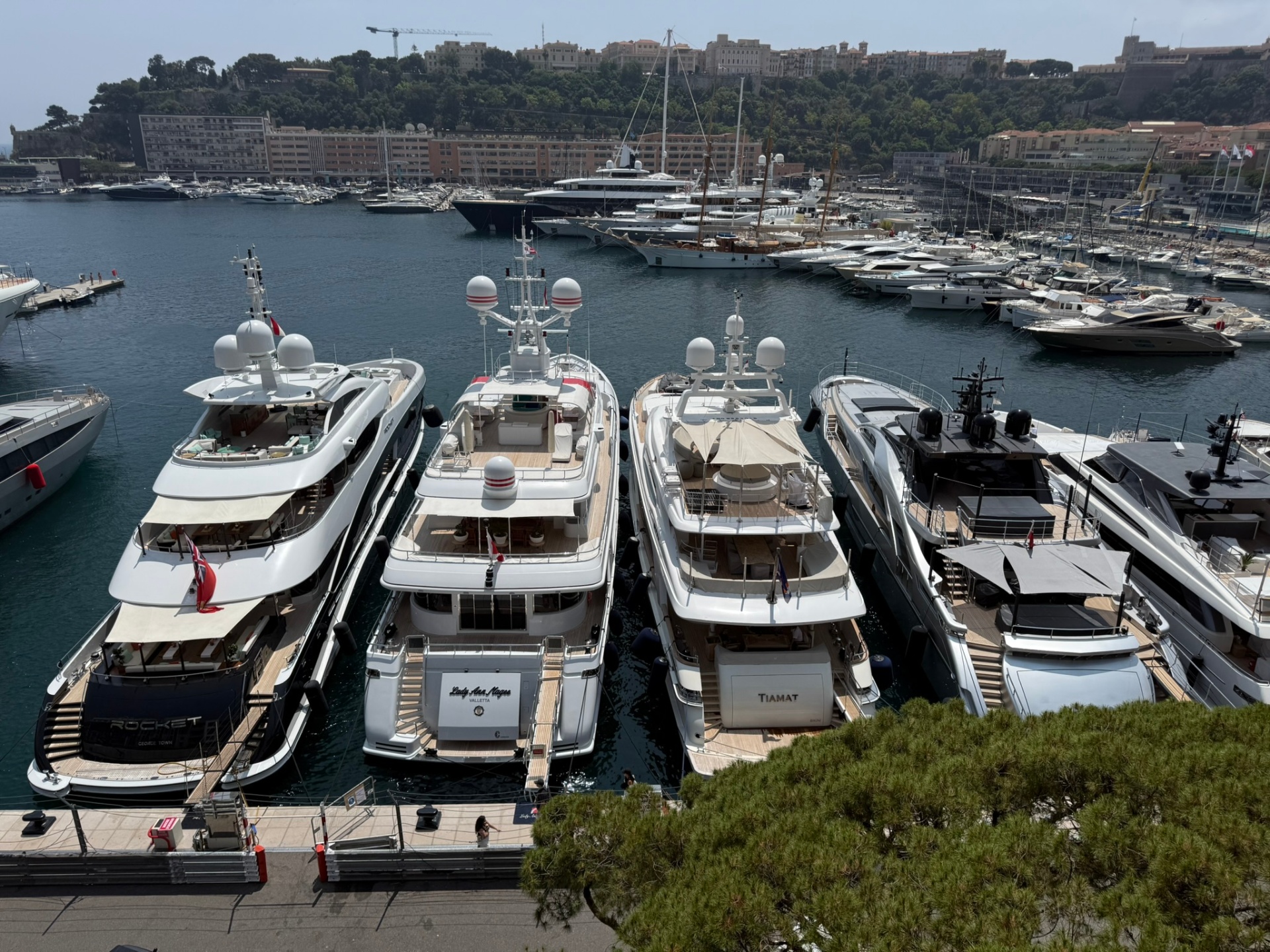 Superyachts moored side by side in Monaco's harbor below the hillside city