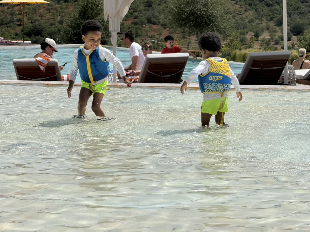 The boys in life jackets wading through the shallow end of the resort pool