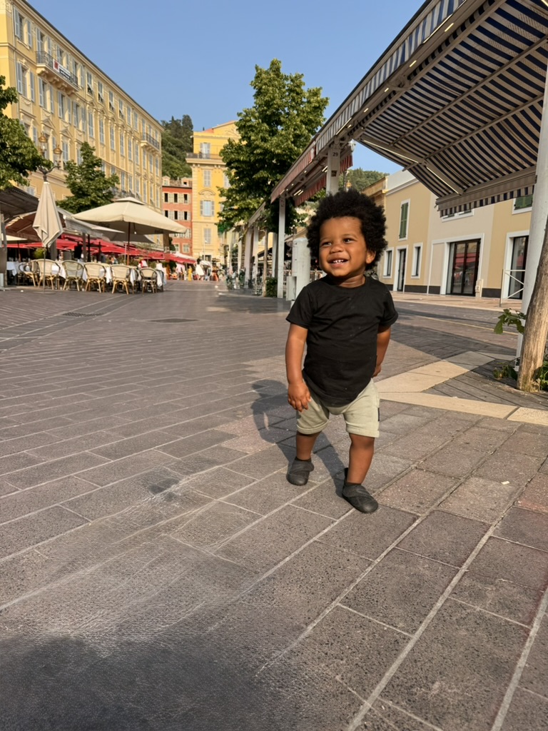 A toddler smiling in the Cours Saleya market square in Old Nice