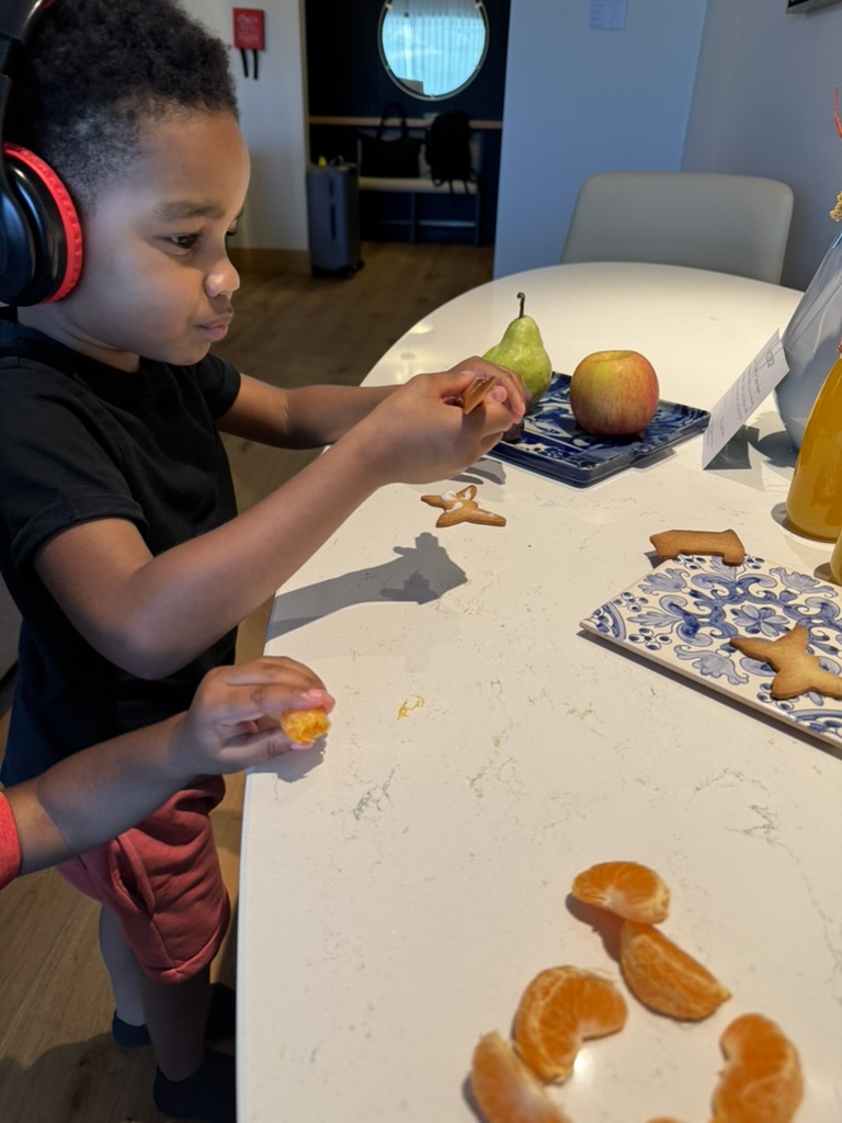 A boy in headphones reaching for cookies and clementine slices on the suite counter