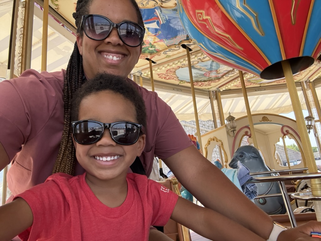 A parent and child smiling together on a colorful carousel in Antibes