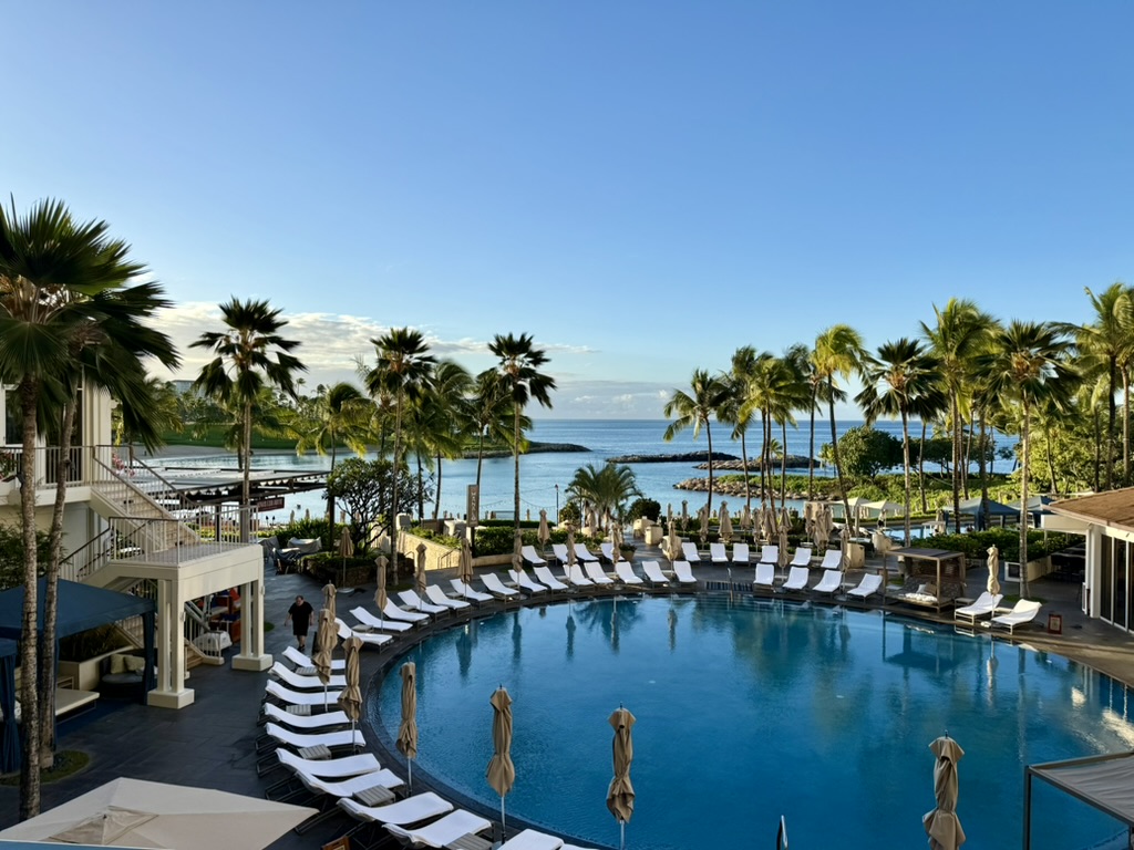 Ko Olina resort pool with palm trees and the ocean beyond in morning light