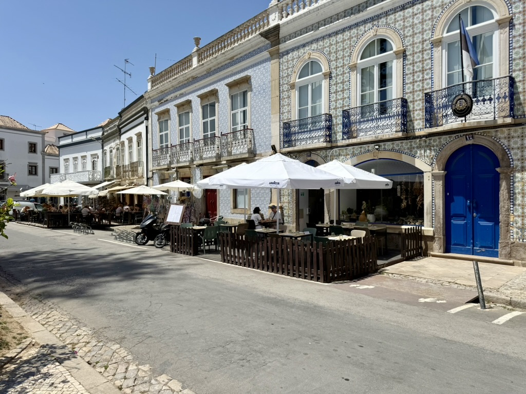 Street in Tavira lined with tiled buildings and white café umbrellas