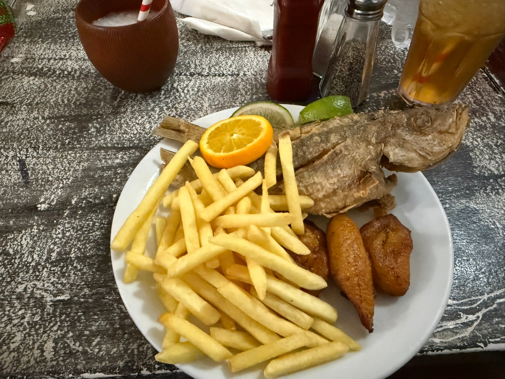 Whole fried fish served with french fries, fried plantains and a citrus garnish at the Fish Fry