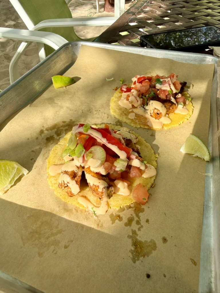 Two fish tacos with pico de gallo and lime on a parchment-lined tray