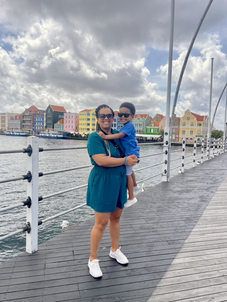 Mother holding her son on the Queen Emma Bridge with the colorful Handelskade behind them