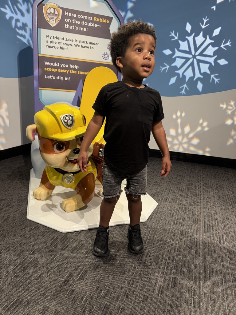 Avery next to the Rubble play station in the snowy rescue area of the PAW Patrol exhibit