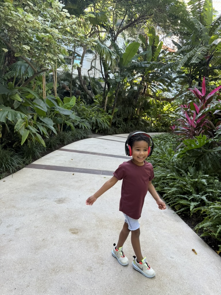 Preston walking a garden path through the resort grounds wearing his headphones