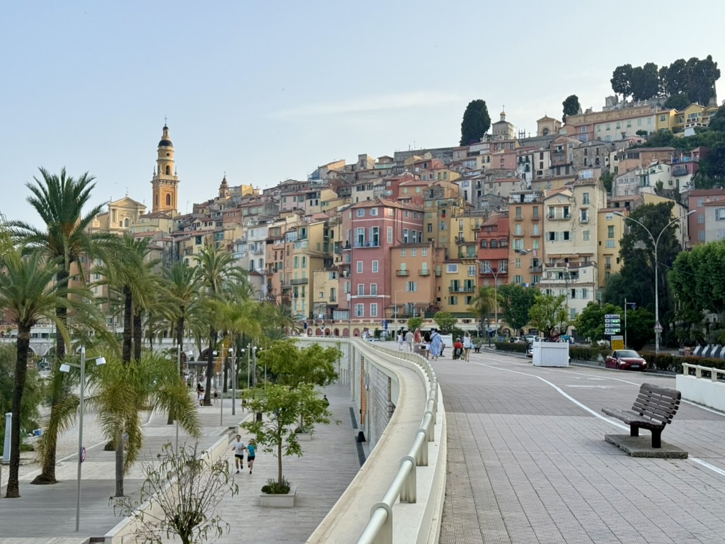 The pastel old town of Menton rising above a palm-lined seafront promenade