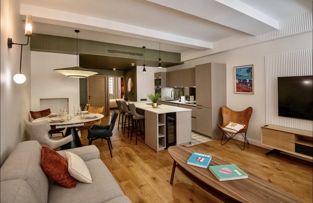 The open living, dining and kitchen space of the Old Nice apartment with warm wood floors and modern furnishings.