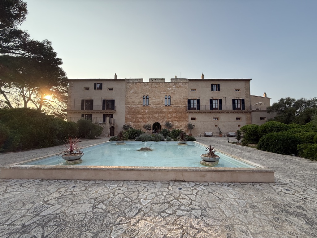 The historic stone estate at Zoetry Mallorca at sunset with a long reflecting pool in the foreground