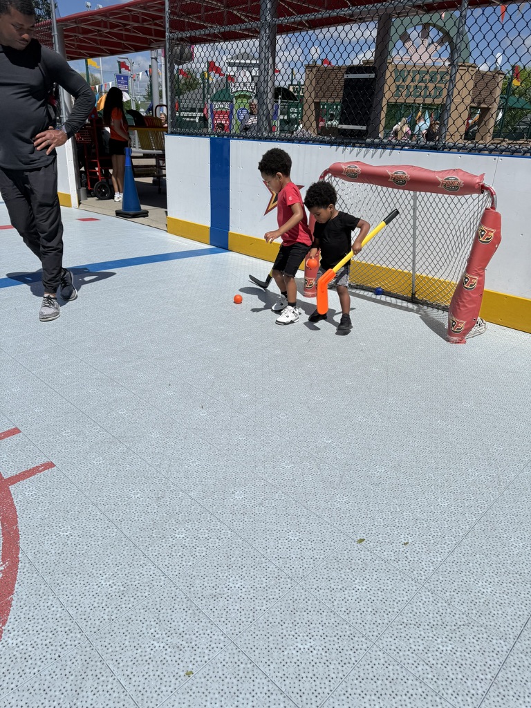 The boys playing street hockey with sticks and a ball on the outdoor rink
