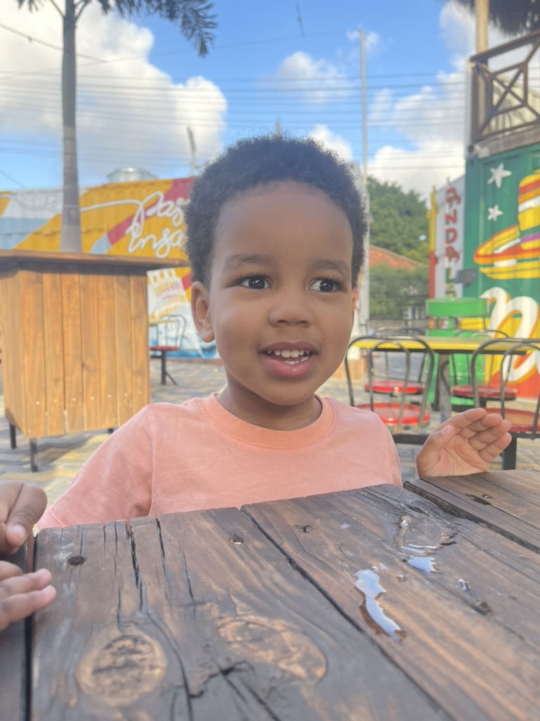 Toddler at a wooden table in front of colorful painted food containers
