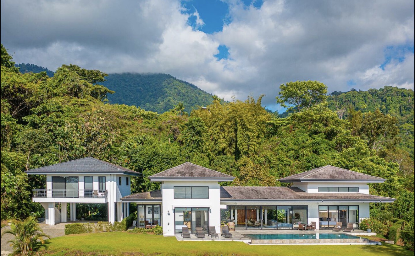 Modern white villa with a pool surrounded by lush green jungle and mountains in Ojochal, Costa Rica