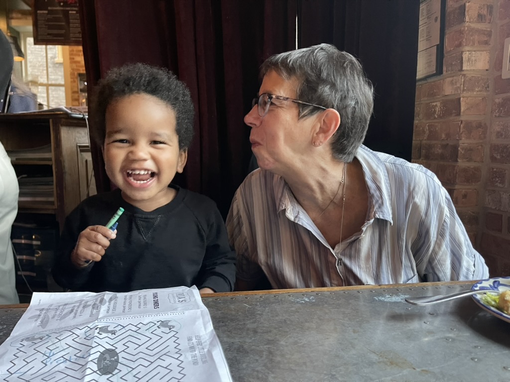 Toddler laughing with his great-grandmother at a restaurant table in Old Town Alexandria