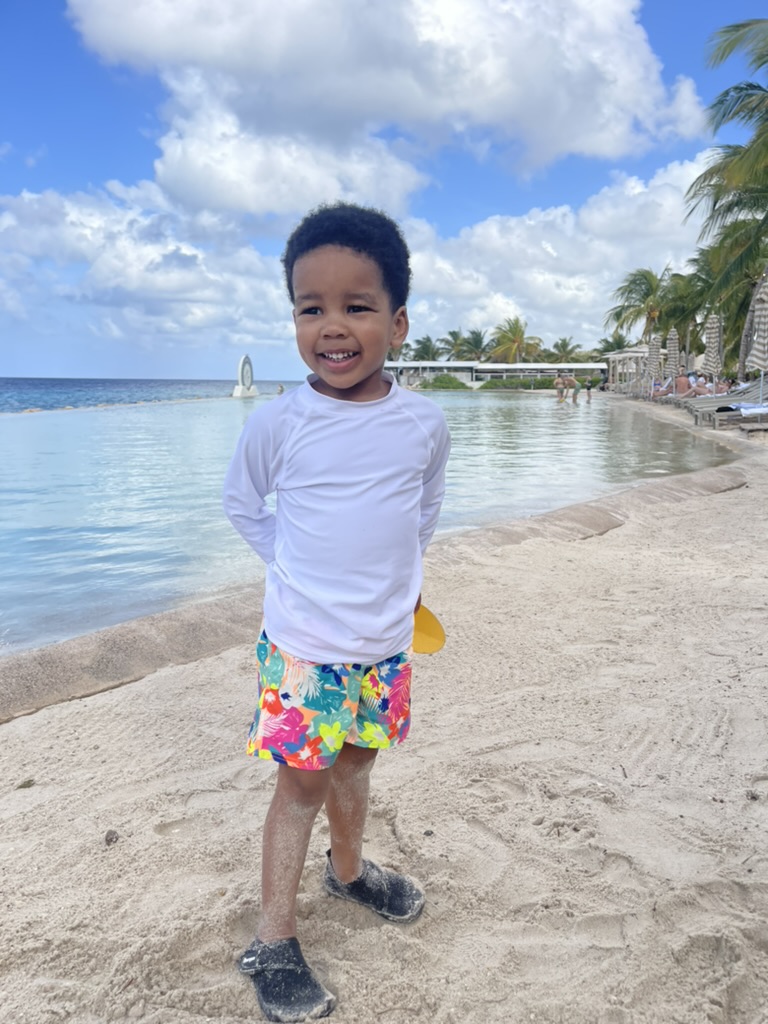 Toddler smiling on the sand beside the protected saltwater pool at Papagayo