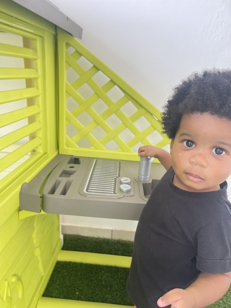 Toddler at the outdoor playhouse kitchen