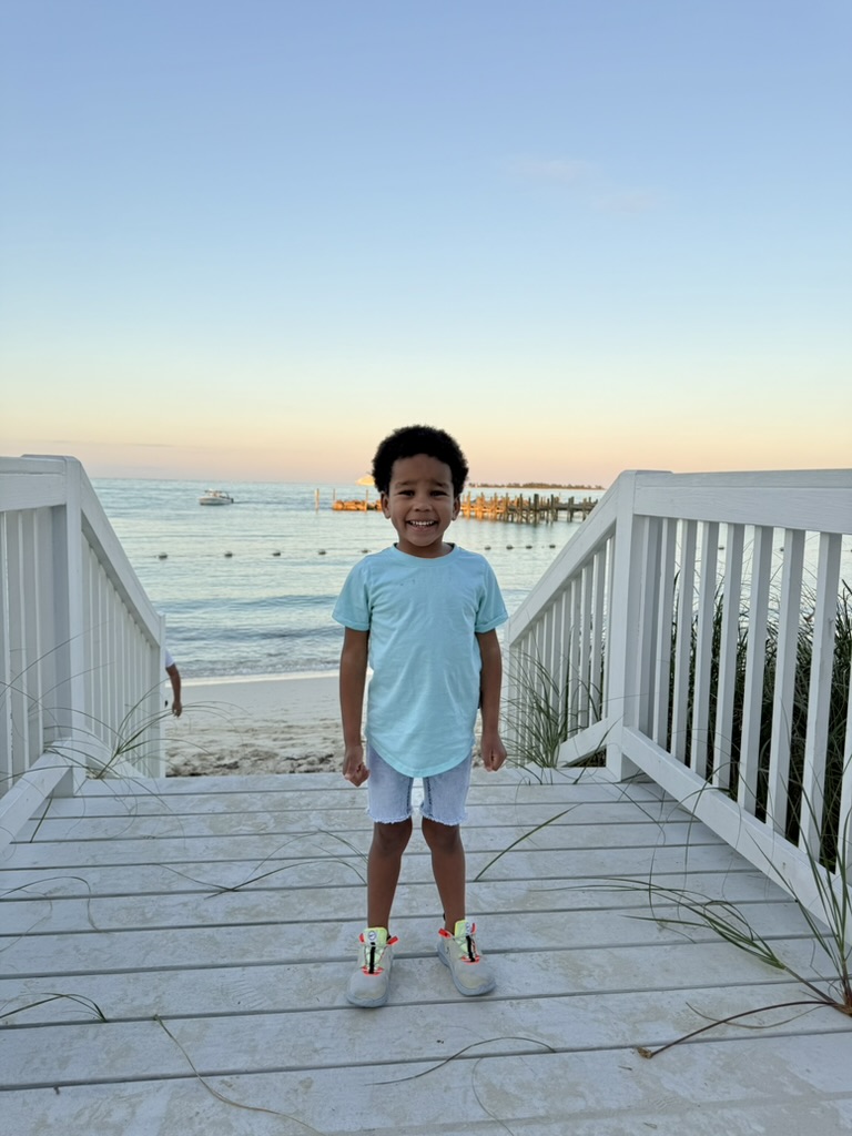 Preston standing on a white wooden boardwalk over Cable Beach at sunset, the ocean and a distant pier behind him