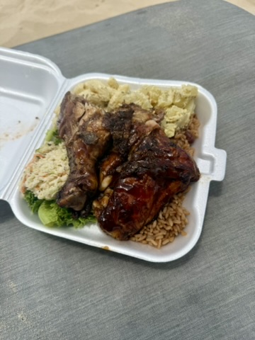 Takeout box of barbecue chicken and ribs with rice, potato salad and coleslaw