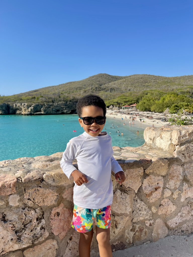 Smiling boy in sunglasses on the stone overlook wall above Grote Knip beach