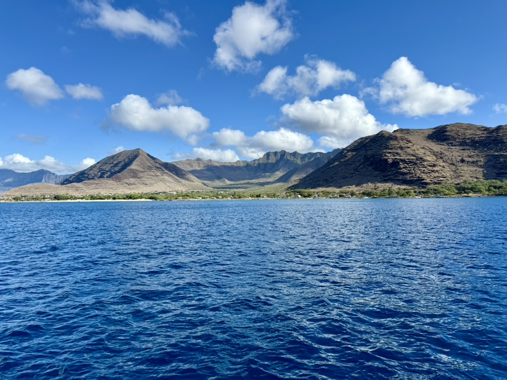 View from the boat of the Waianae mountain range and coastline across deep blue water
