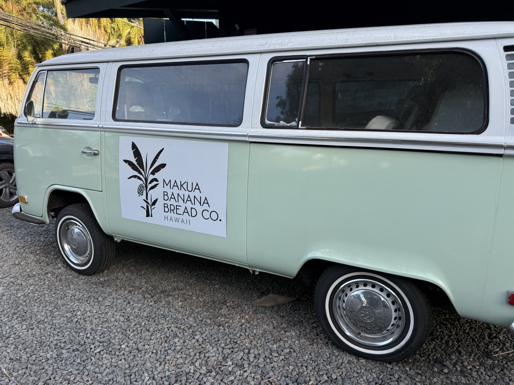 A mint green vintage van with a Makua Banana Bread Co. Hawaii sign on its side