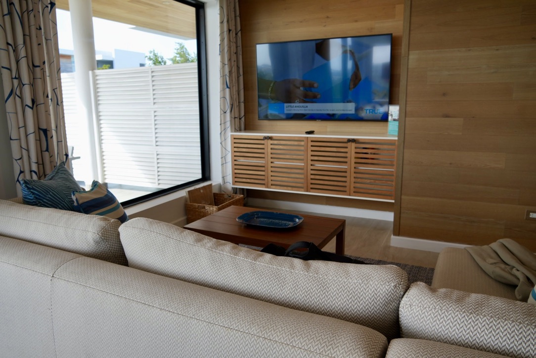 Villa living room with sectional sofa, wood-panelled wall and ocean-side window