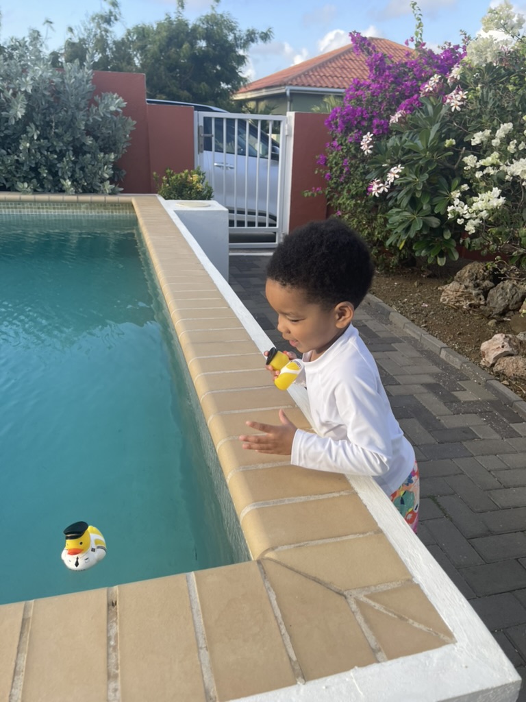 Toddler beside the plunge pool watching a rubber duck float