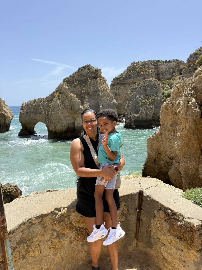 Mom holding her son at a stone viewpoint in front of the Ponta da Piedade sea arches