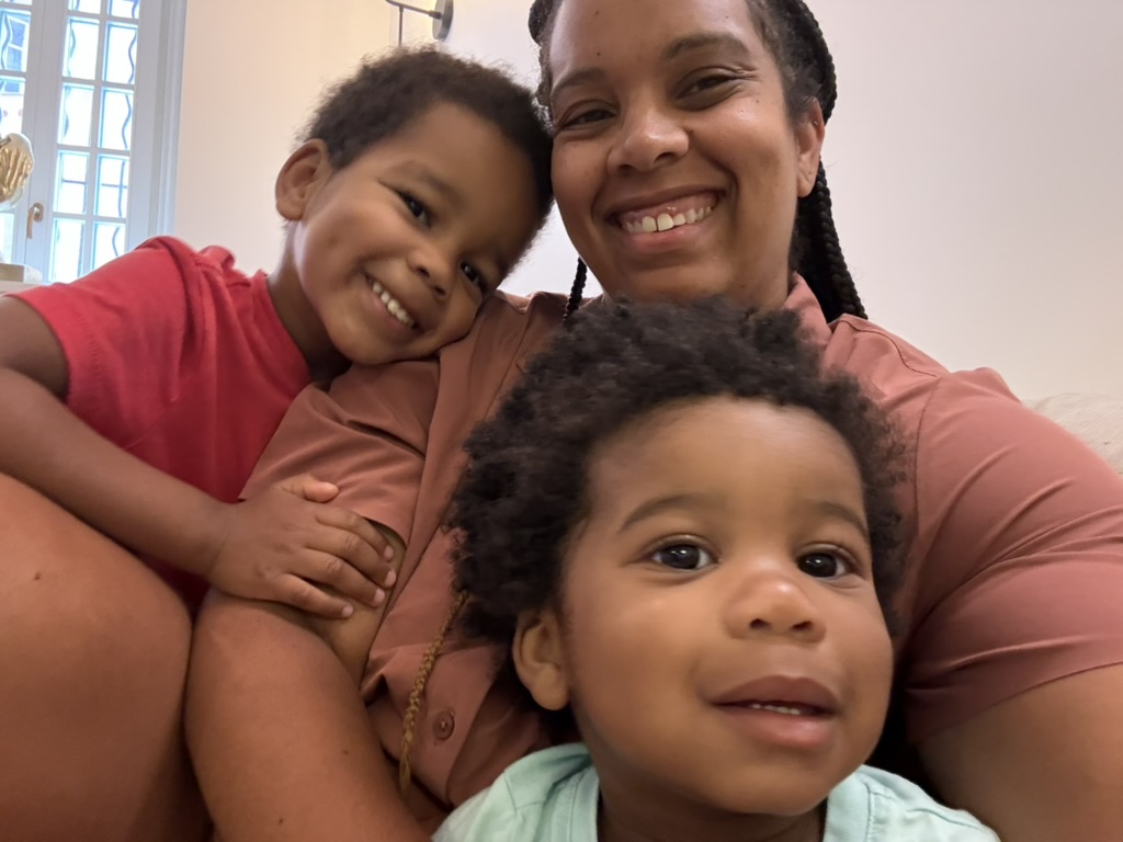 A smiling mother holding her two young sons close for a family selfie